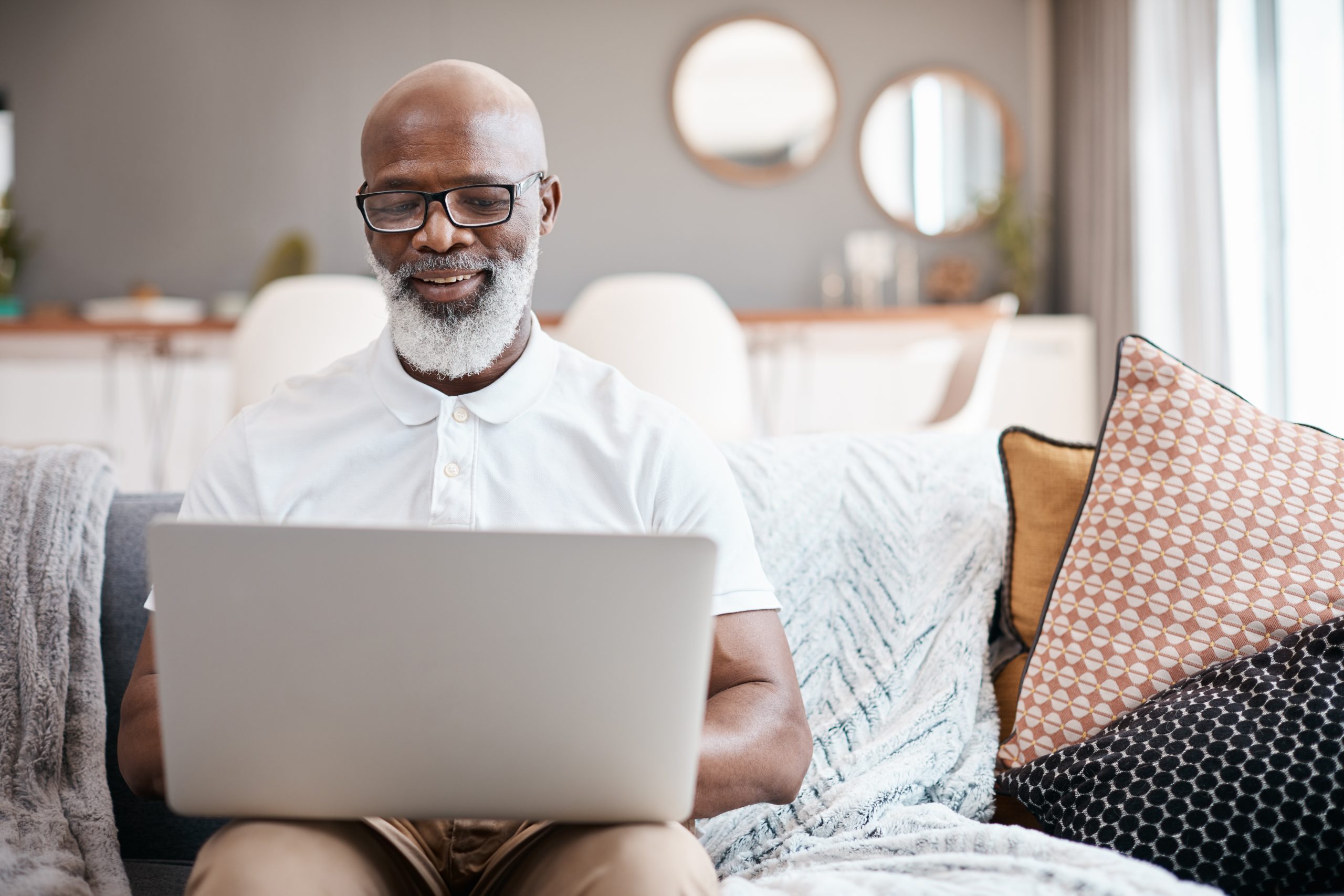 A man sits on a couch typing on his laptop. It takes work, and several steps to get Social Security Disability in Utah.