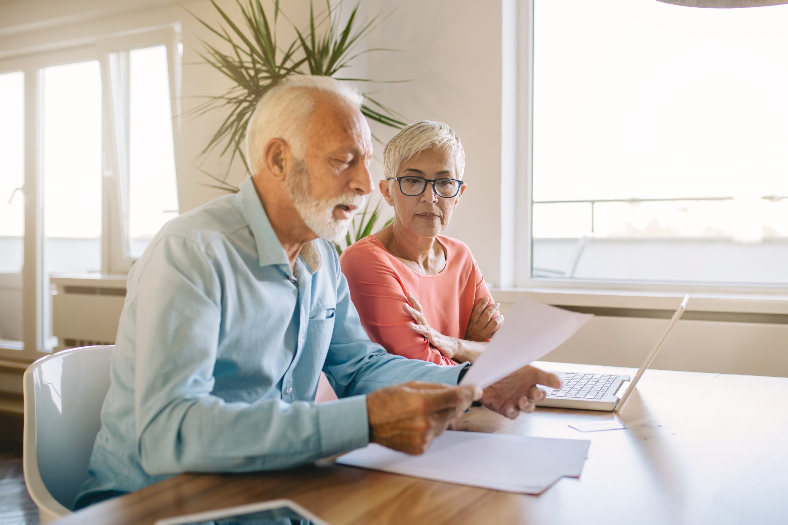 A woman and man sit at a table by a window looking at papers and a laptop. A lawyer can make it easier to apply for disability benefits.