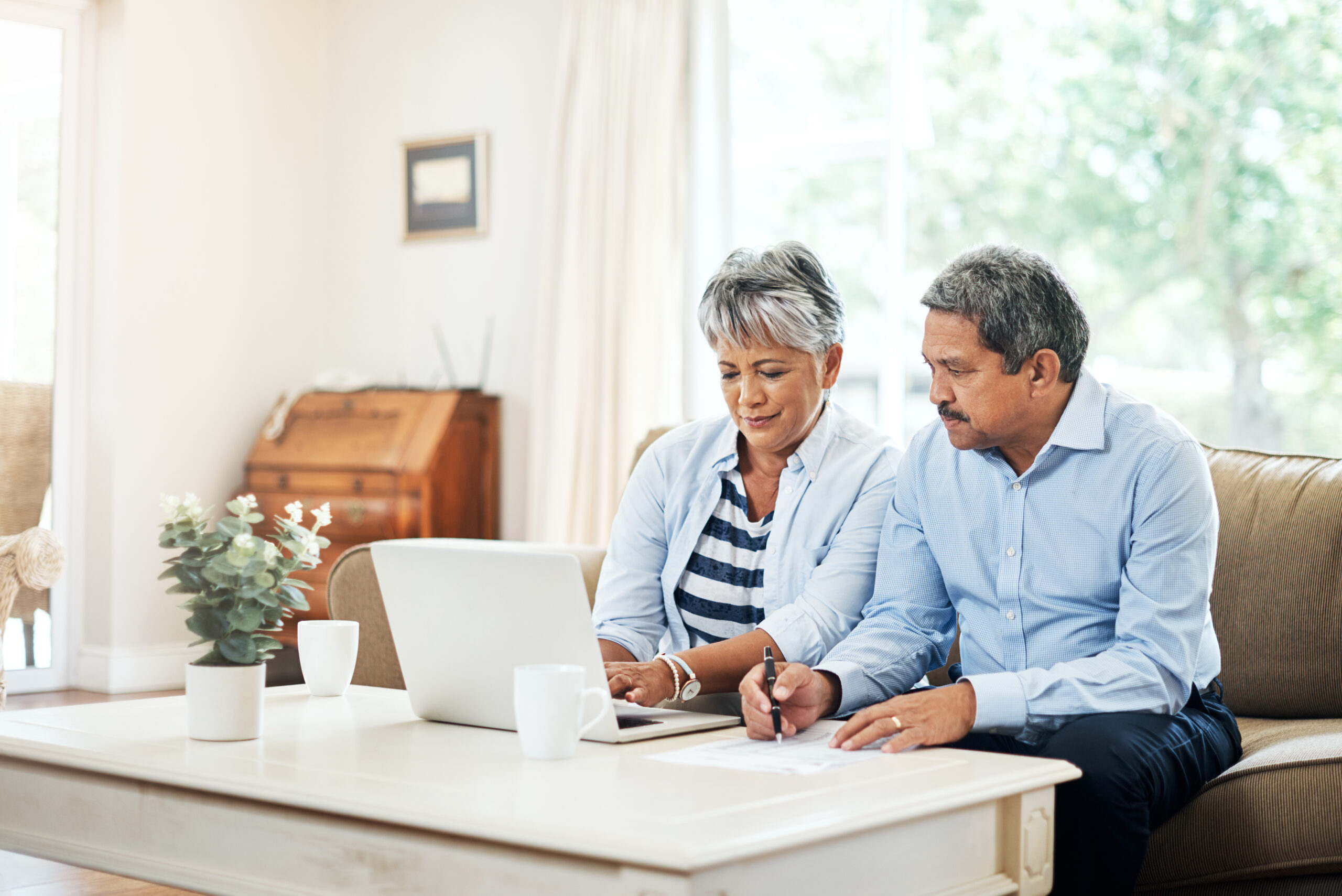 A couple sits on a couch, looking at a laptop and papers on the coffee table. Social Security Appeals include several steps to keep track of.