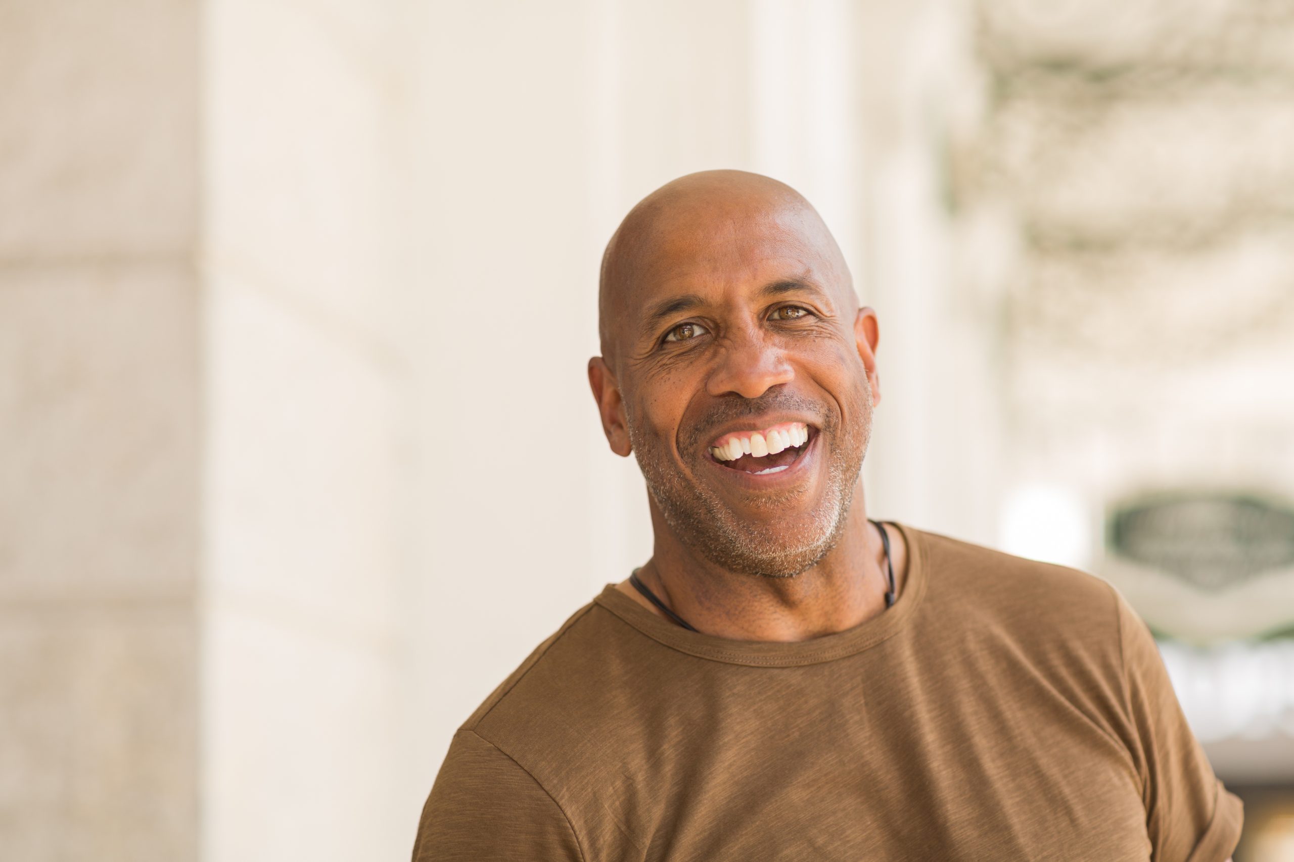 Standing outside by a stone building wearing a T-shirt, a man smiles for the camera. Feel more confident about how Social Security Disability works with answers to disability FAQs from Barnes Disability.
