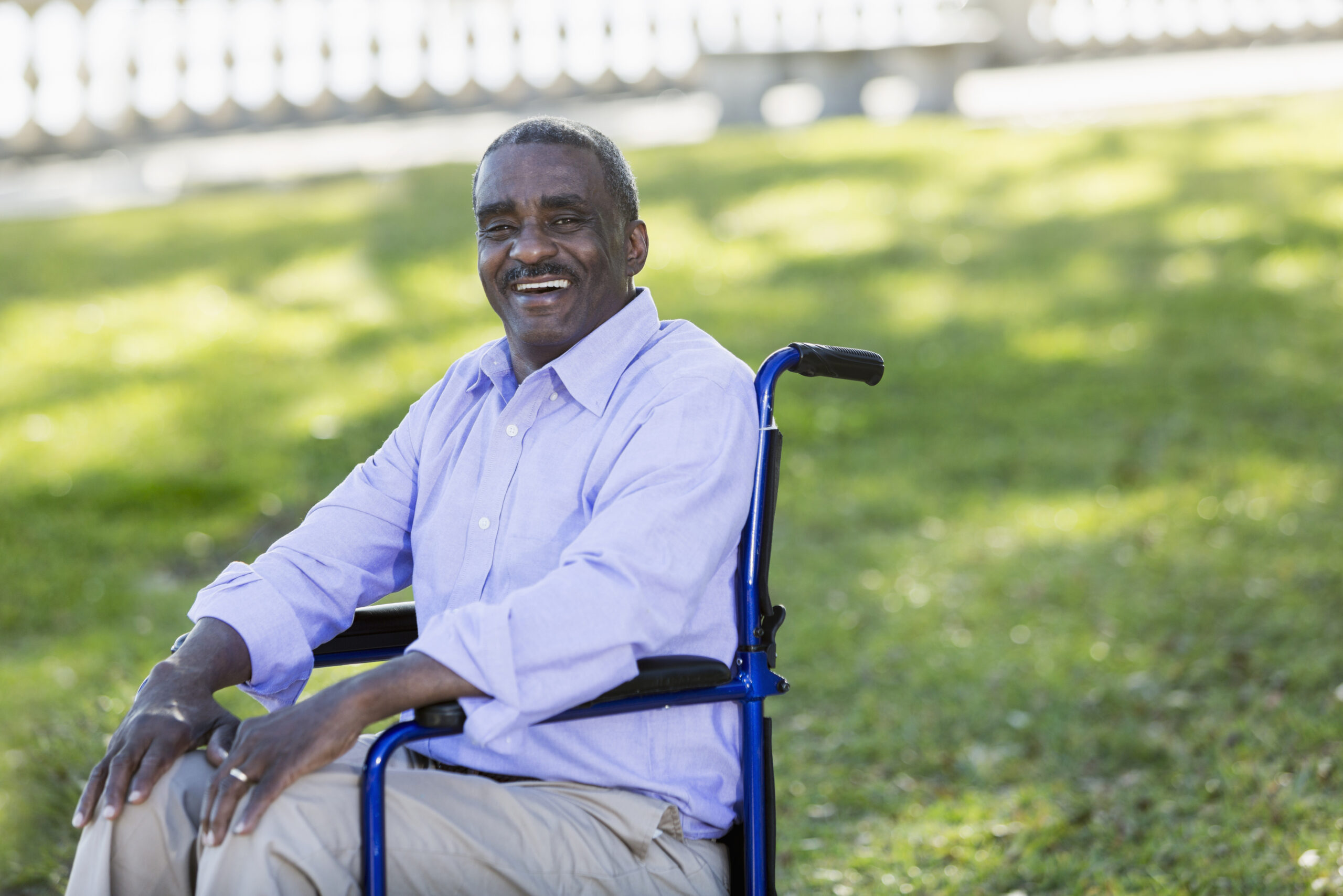 A man sits in a wheelchair in park, smiling for the camera. You can get a financial boost after a work-stopping health problem with help from long-term disability insurance lawyers in Utah.
