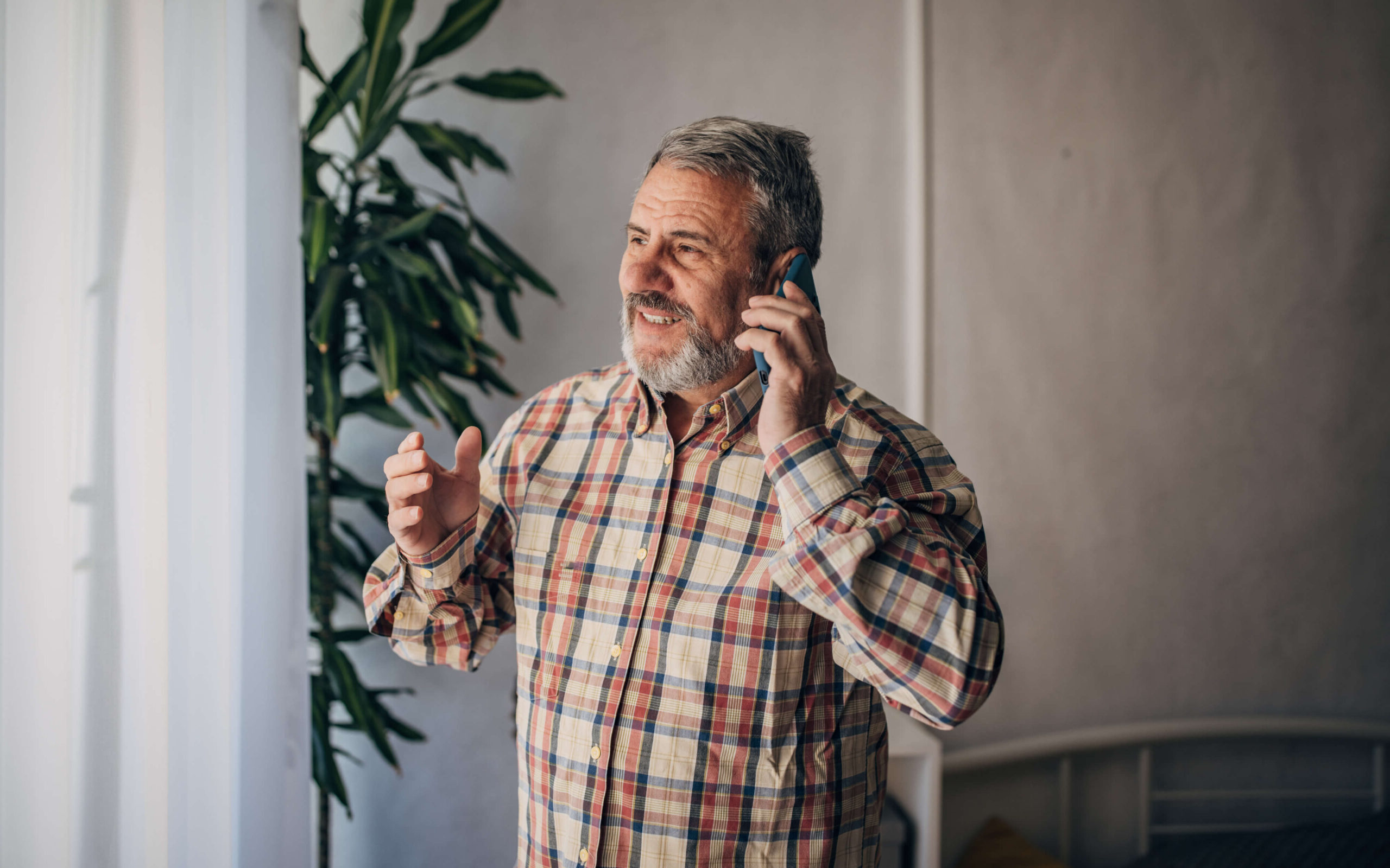 A man talks on the phone, smiles and gestures, looking out a window. Call Barnes Disability for help with Social Security Disability Insurance (SSDI), Supplemental Security Income (SSI) or long-term disability insurance.