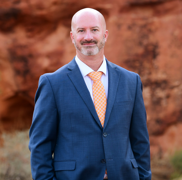 Portrait of Matt Ormsby, a Utah SSD attorney at Barnes Disability Advocates focusing on disability hearings, in front of red rocks.