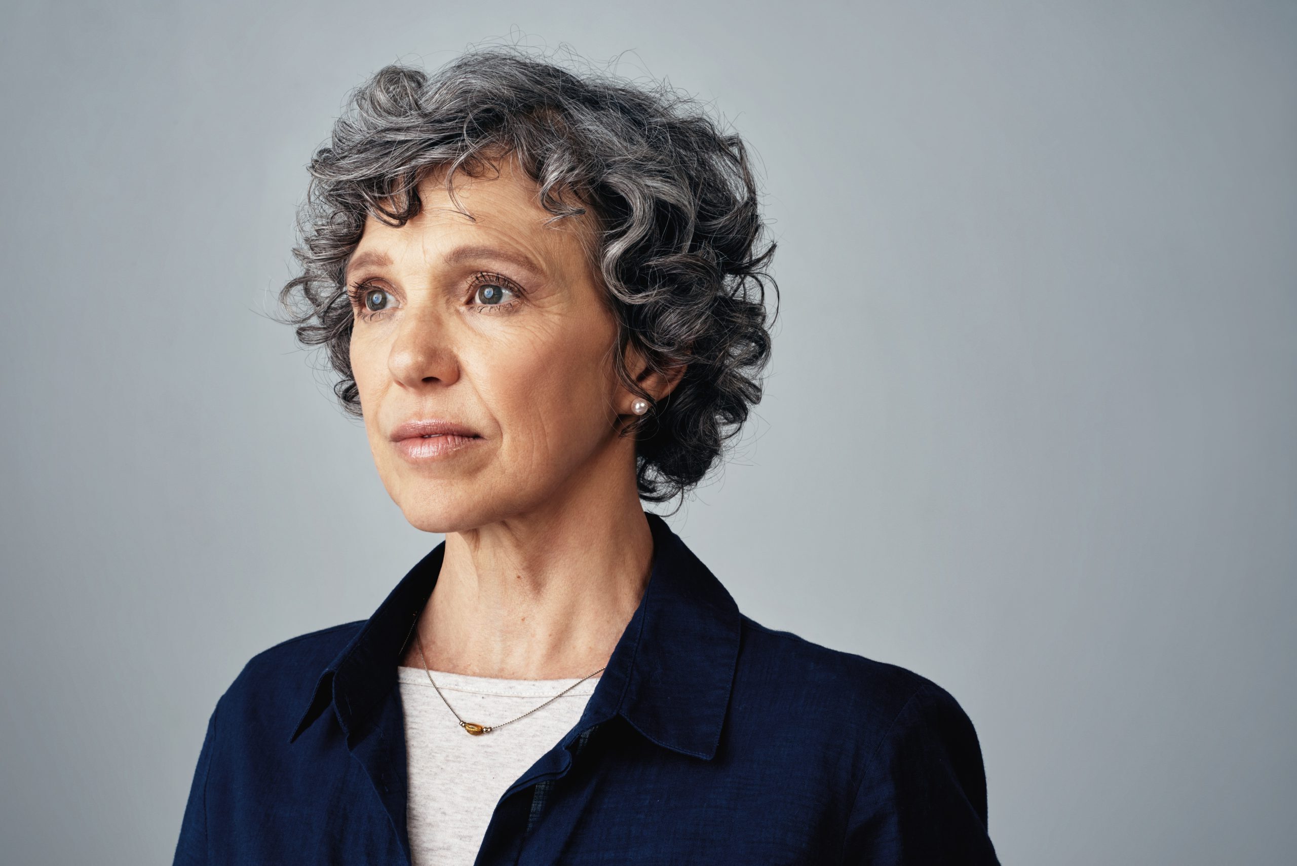 Portrait of a woman looking to the distance. To know if you qualify for Social Security Disability, you have to see if your case meets strict rules.