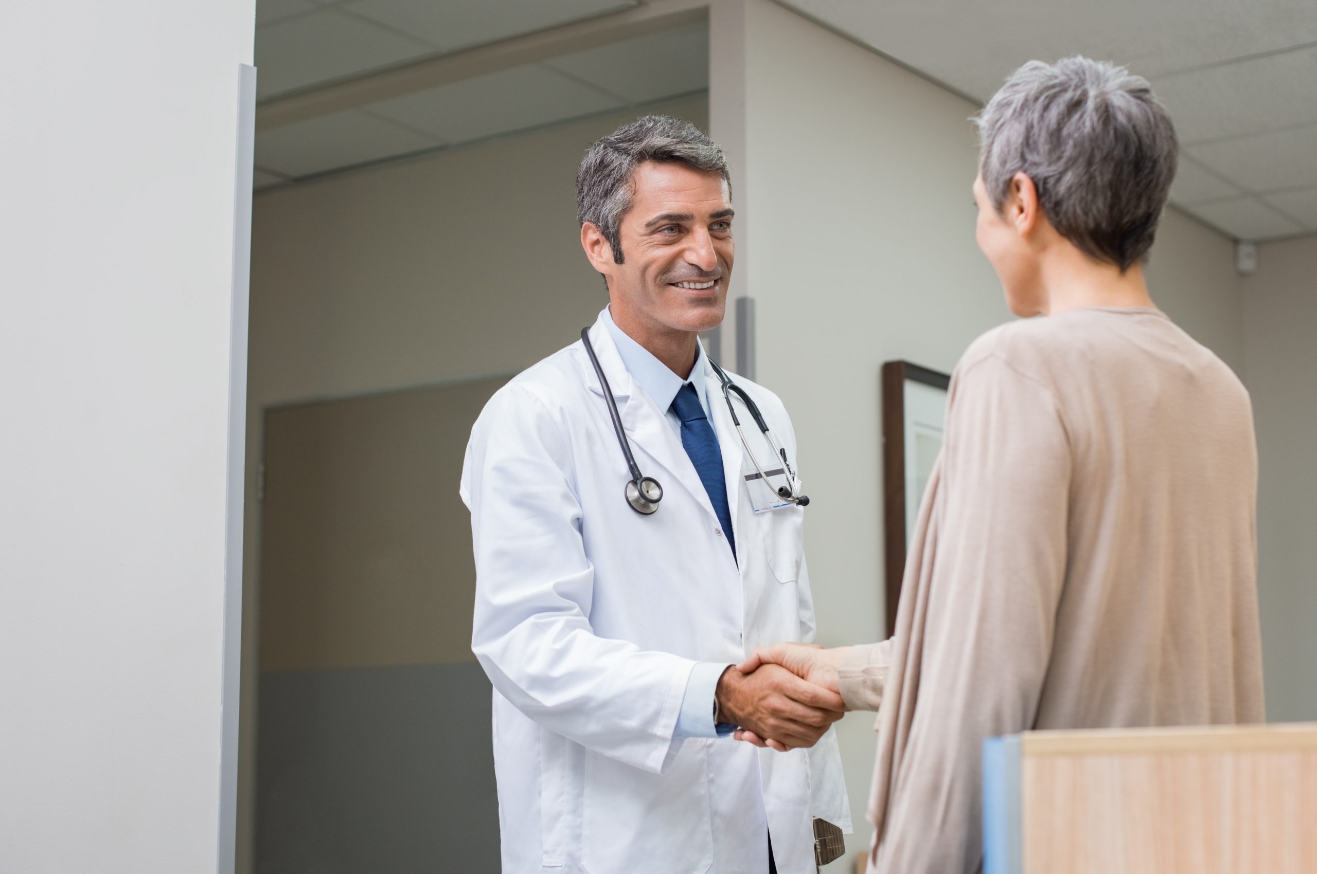 A woman shakes hands with a doctor in a white coat and stethoscope. Doctors’ reports and medical test results are key to qualifying for Social Security Disability.
